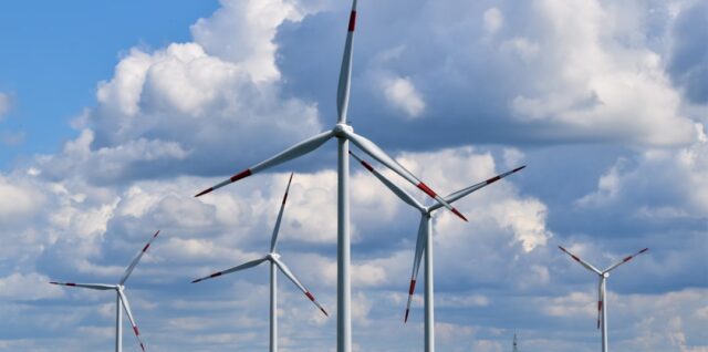white wind turbines on green grass field under blue and white cloudy sky during daytime